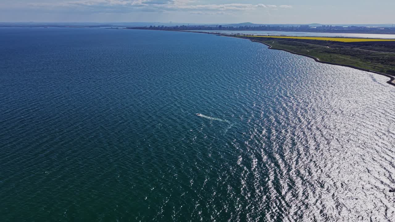 Barche e onde al molo vicino alla riva con lo skyline della città in lontananza.