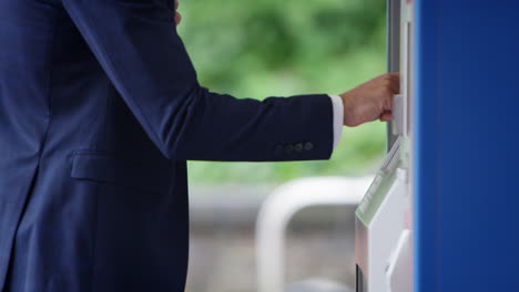 close up of businessman commuting making contactless payment for train ticket at machine with card