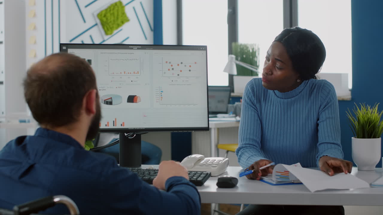 Handicapped businessman and african employee working at financial project