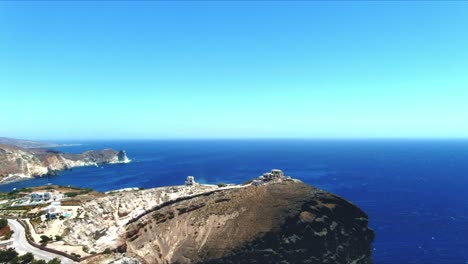 vista aérea 4k azul del mar y el cielo del acantilado del pueblo de akra mavro vouno con veleros atracados en la distancia en santorini grecia