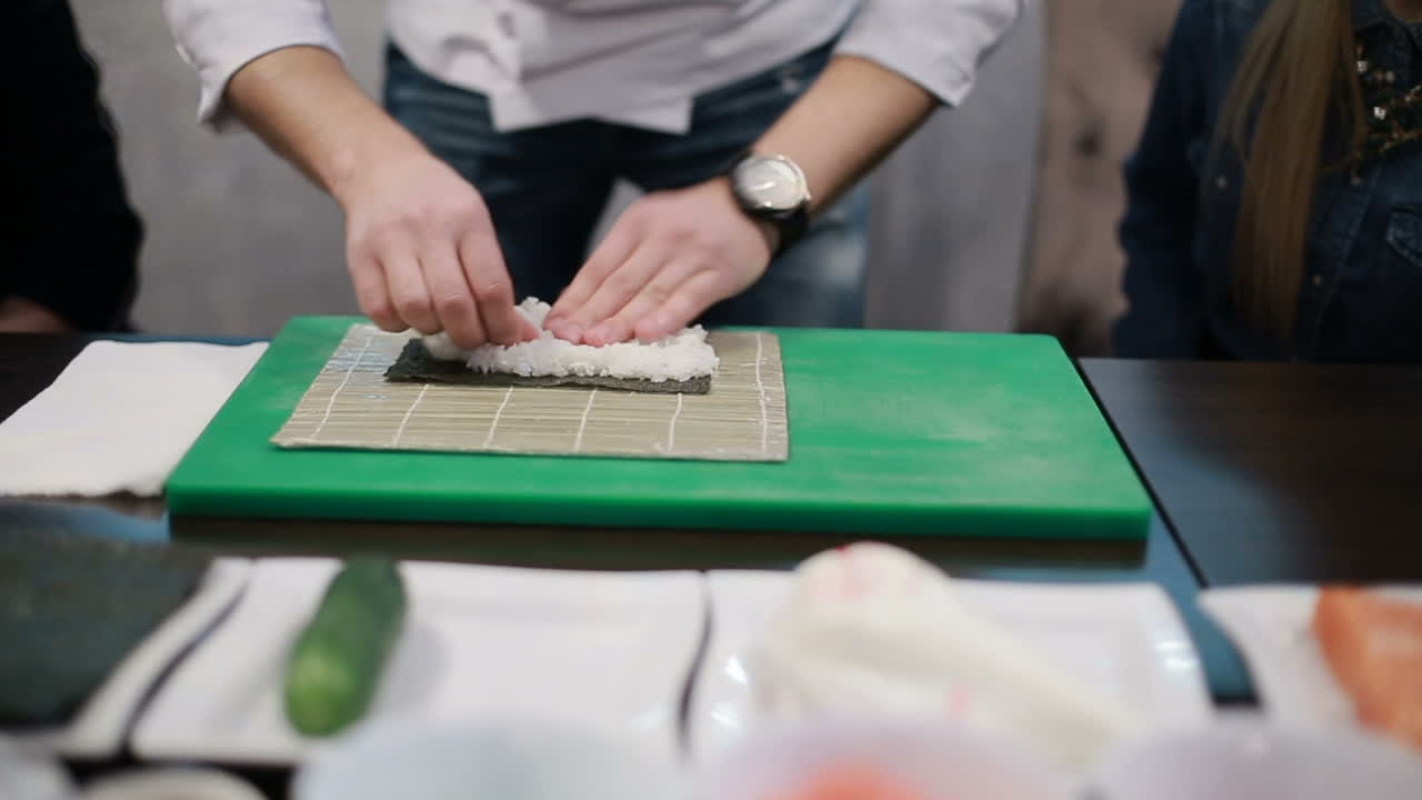 Preparing Sushi Set. Closeup of man chef putting japanese sushi rolls with rice