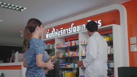 caucasian male pharmacist selling prescription medicine to customers.