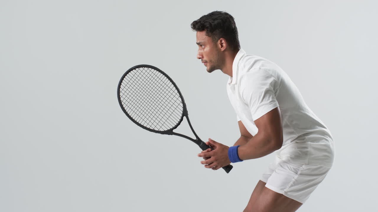 Young biracial man poised to hit a tennis ball, with copy space