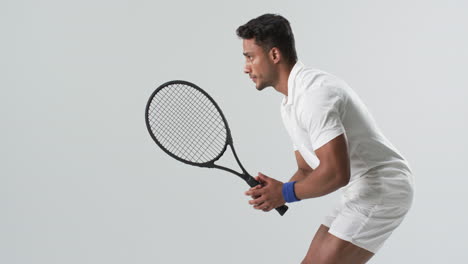 young biracial man poised to hit a tennis ball, with copy space