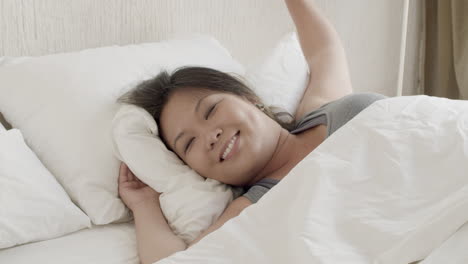 medium shot of happy japanese woman waking up and stretching