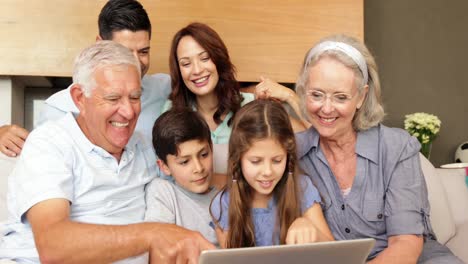 familia extendida usando la computadora portátil juntos en el sofá