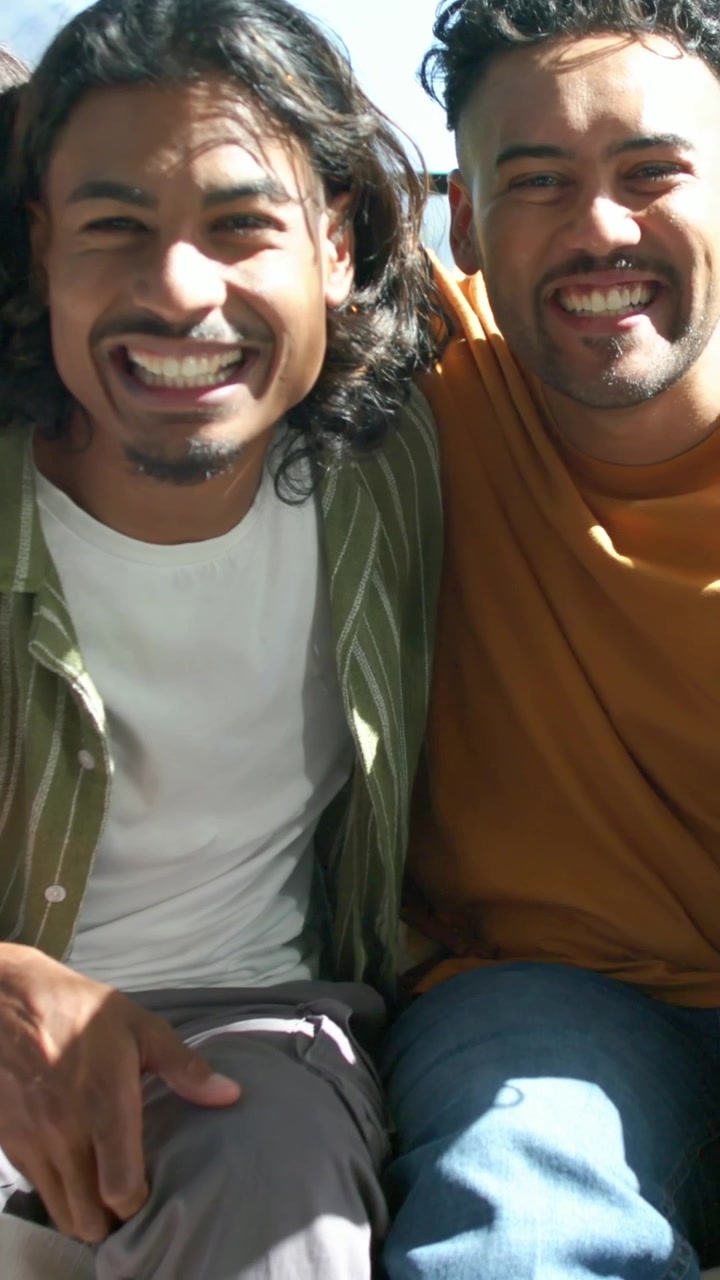 Vídeo vertical: Trio sorridente posando para a câmera no sofá perto da janela com a mão tocando o ombro