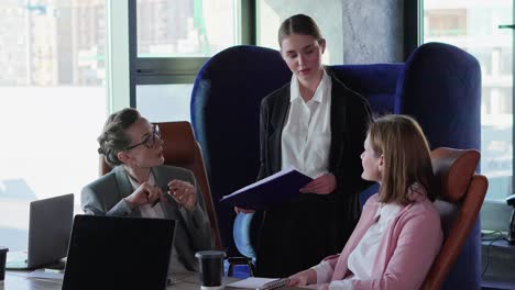 A-confident-blonde-girl-in-business-clothes-a-businesswoman-tells-her-colleagues-about-upcoming-plans-and-possibilities-for-solving-their-problem-and-question-during-a-meeting-in-a-modern-office-at-the-table