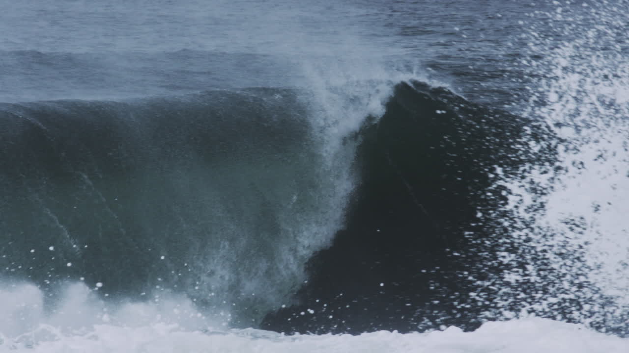 Barrel shape begins to form as wave thickens and light hits mist above curling water, slow motion