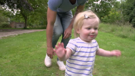 toddler in garden learning to walk with father