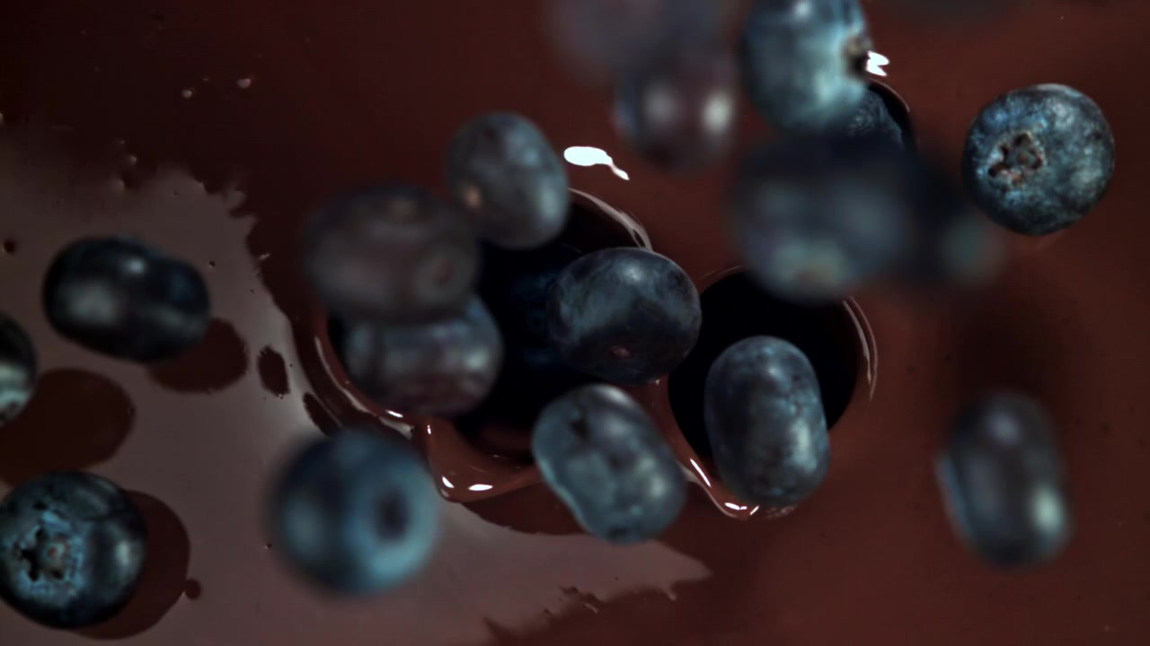 Movimento rallentato di mirtilli che cadono nel cioccolato fuso