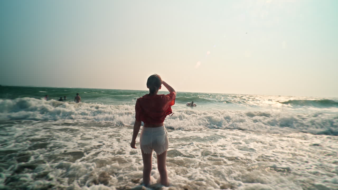 Woman on a beach looking at the ocean