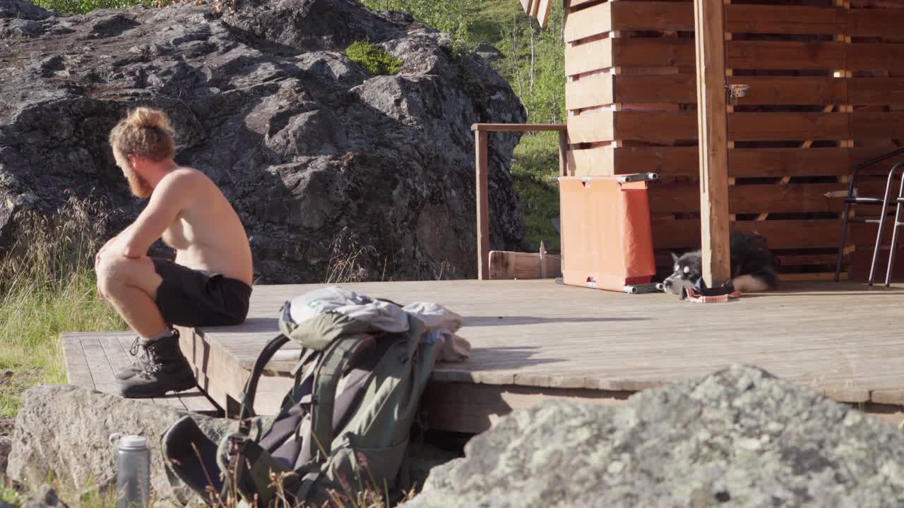 노르웨이 lyngsdalen에서 화창한 날 동안 나무 오두막에 반쯤 벗은 청년