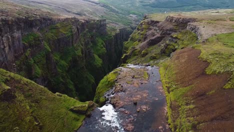 cascada glymur desde arriba con pájaros volando en barranco, islandia, vista aérea
