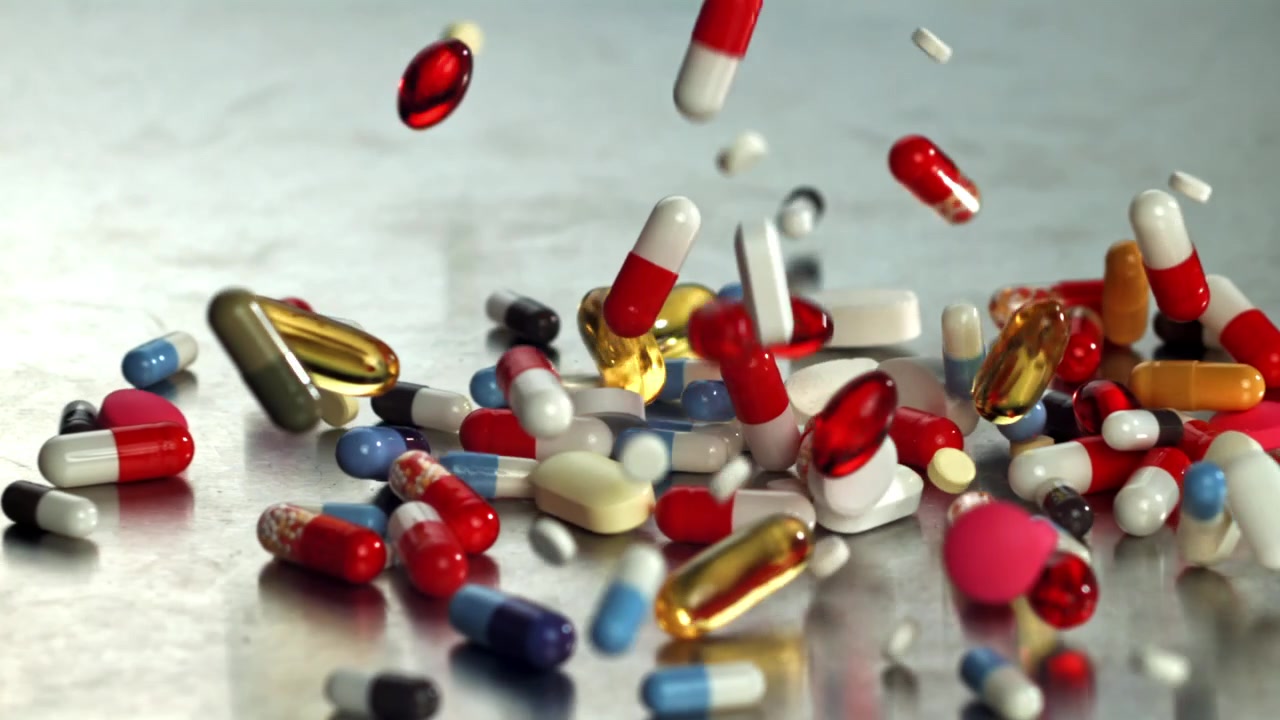 Colorful Pills and Capsules Falling onto a Metallic Surface