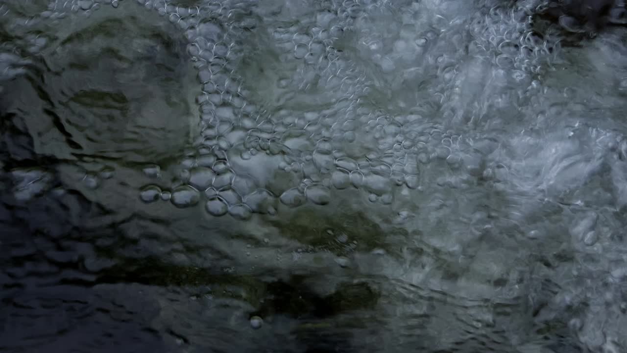 Stream crystal clear water and bubbles. Close Up.
