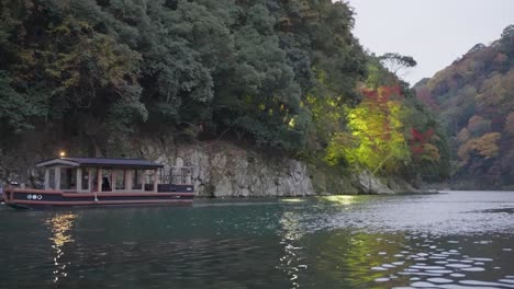 boat travels up katsura river at arashiyama in late fall in japan