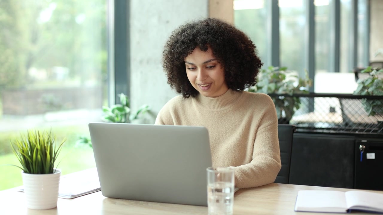 Jovem Mulher Trabalhando no Laptop e Revisando Documentos em Escritório Moderno