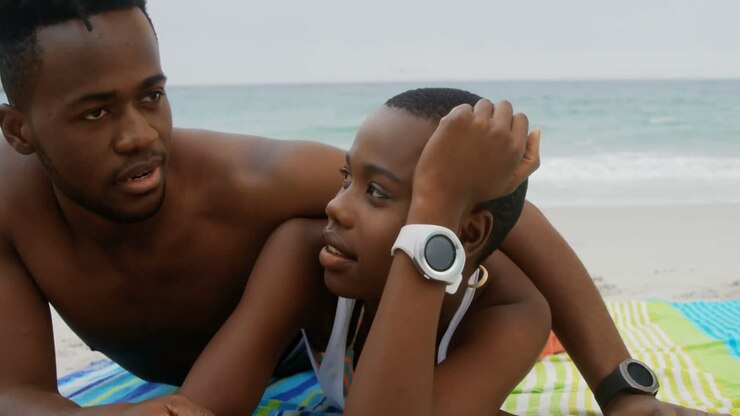 Coppia afroamericana ripresa frontalmente mentre si rilassa sulla spiaggia 4K