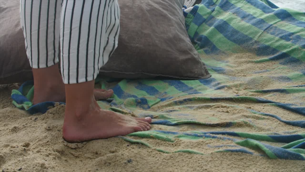 Zachtjes waaiende wind over strandlandschap terwijl een blootvoetse volwassene stilstaat