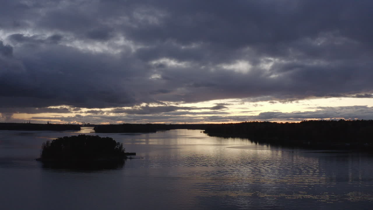 Lille ø midt i en sø med regnfulde skyer på himlen sent om aftenen