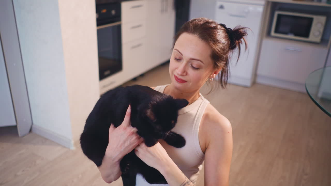 Joyful Pet Bond, Woman Embraces Large Black Cat Happily, Kitchen Scene Showing Woman Hugging Black Cat With Affection, Woman Shows Love Through Hug With Large Black Feline In Kitchen Setting