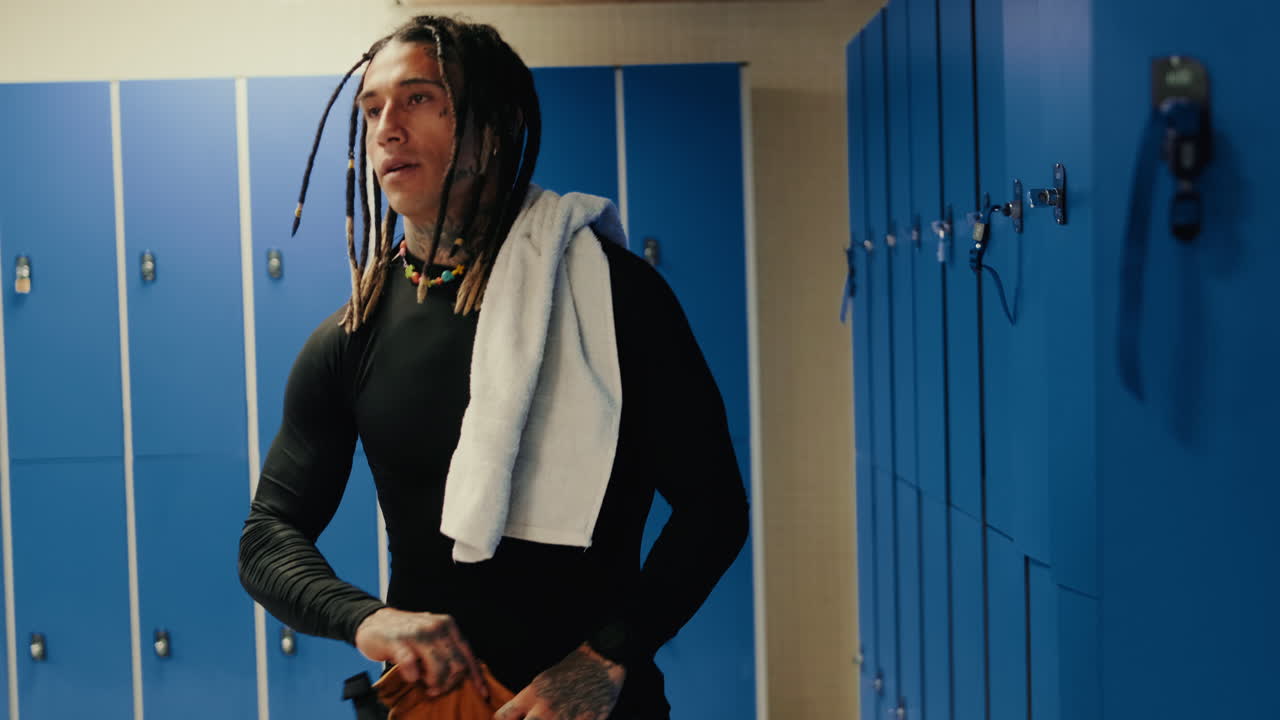 Homem com dreads abrindo armário no vestiário da academia