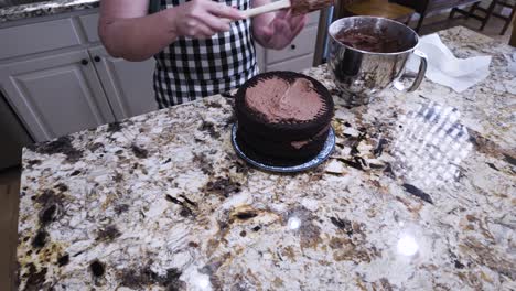 Frosting-a-three-layer,-homemade,-made-from-scratch,-chocolate-cake---tilt-down