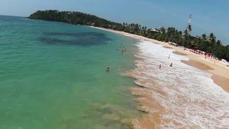 drone aéreo sobre turistas nadando en la popular playa con agua turquesa en la zona tropical de sri lanka