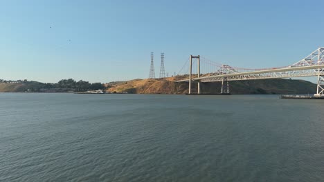 layers of concrete, steel, and sea come into view as the drone pans over crockett toward the structured silhouette of the alfred zampa bridge