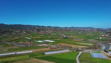 Village-Greenhouses-and-Cultivated-Land-in-Spring:-Agriculture-Flourishing-in-a-Beautiful-Valley-Surrounded-by-Majestic-Mountains-in-Albania