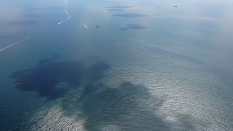 this captivating aerial view highlights various textures in the ocean as boats cruise across the calm waters under a clear sky. sunlight reflects beautifully on the surface creating patterns.
