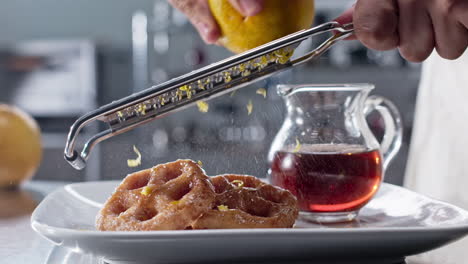 orange zest over fritters back and forth, slow motion