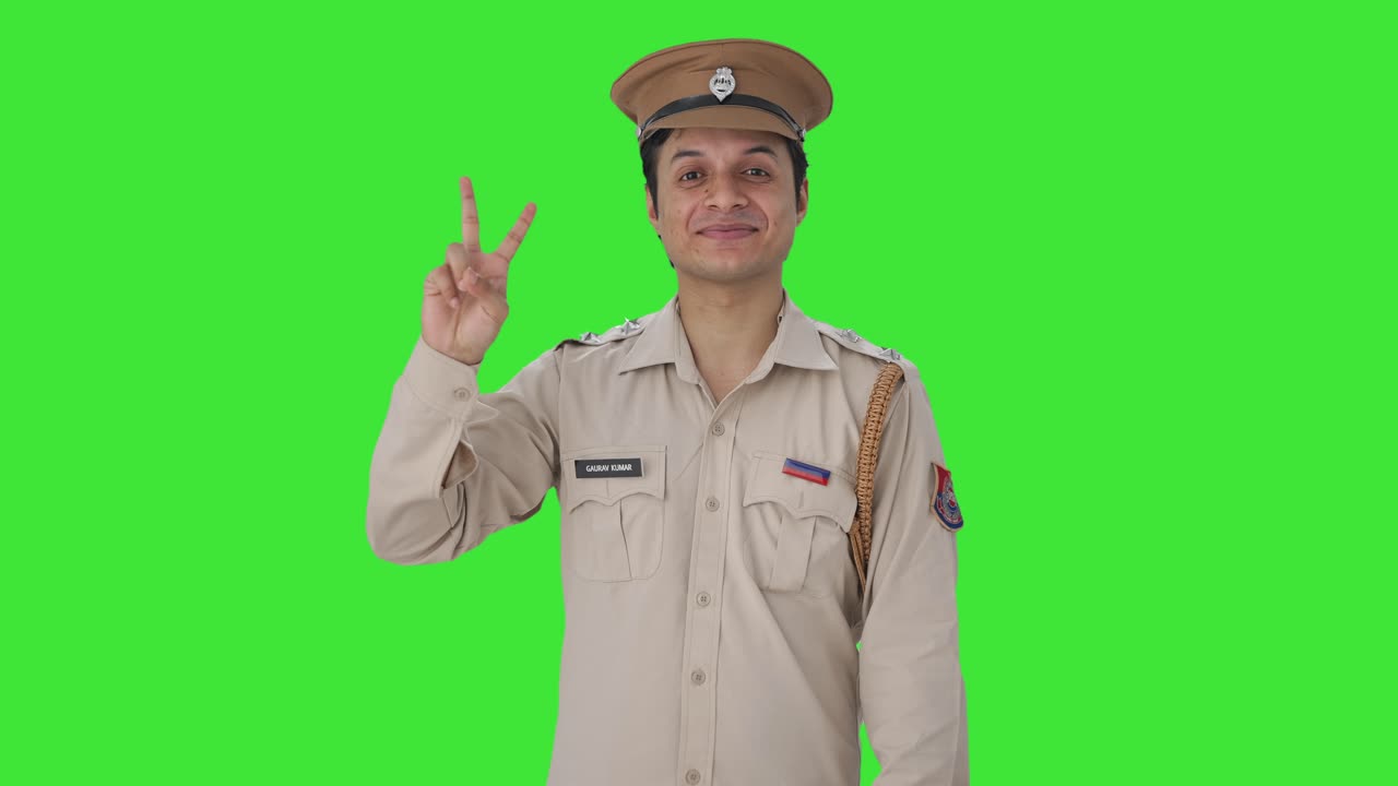 oficial de policía indio feliz mostrando el signo de victoria pantalla verde