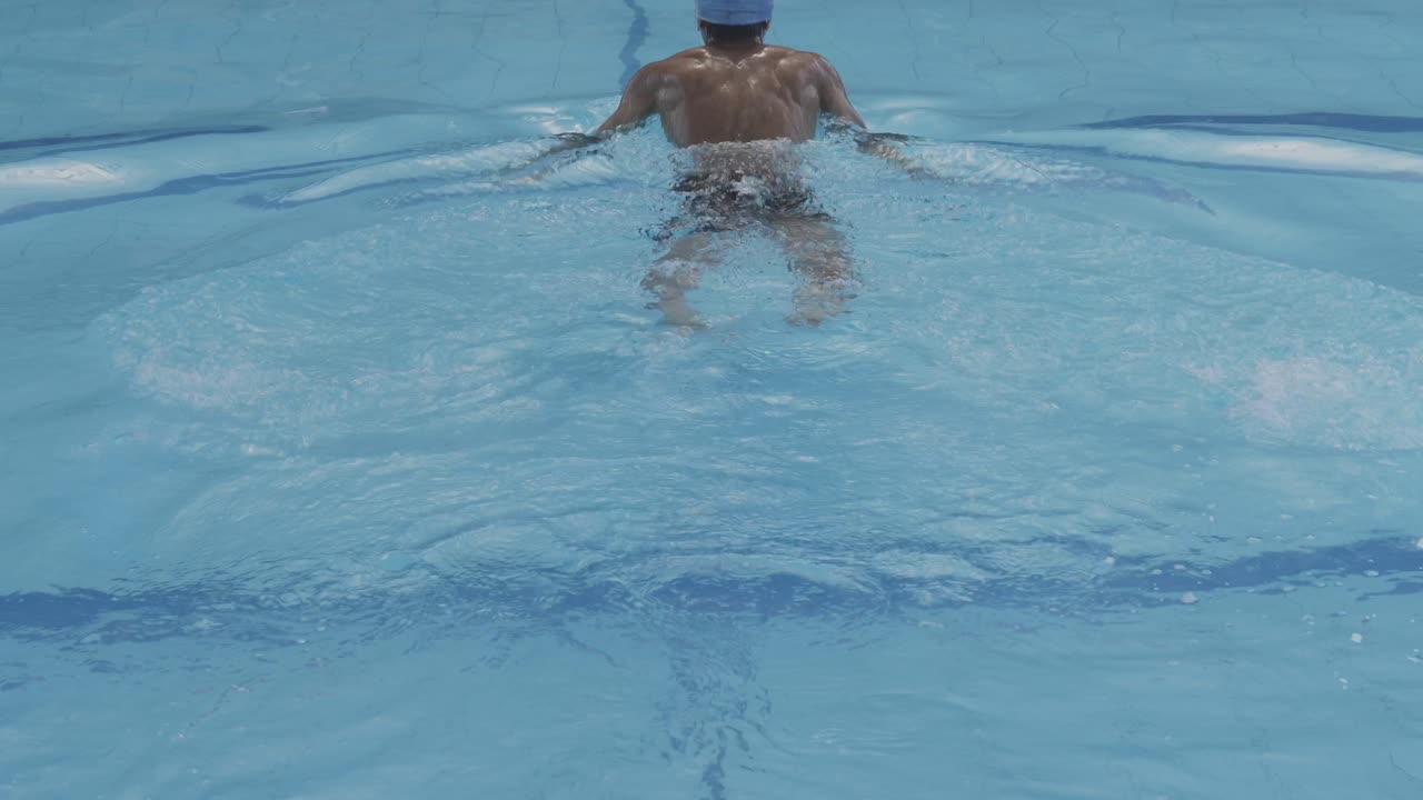 Back View Of Young Swimmer Swimming In The Pool, Dive And Doing Frog Style Swim