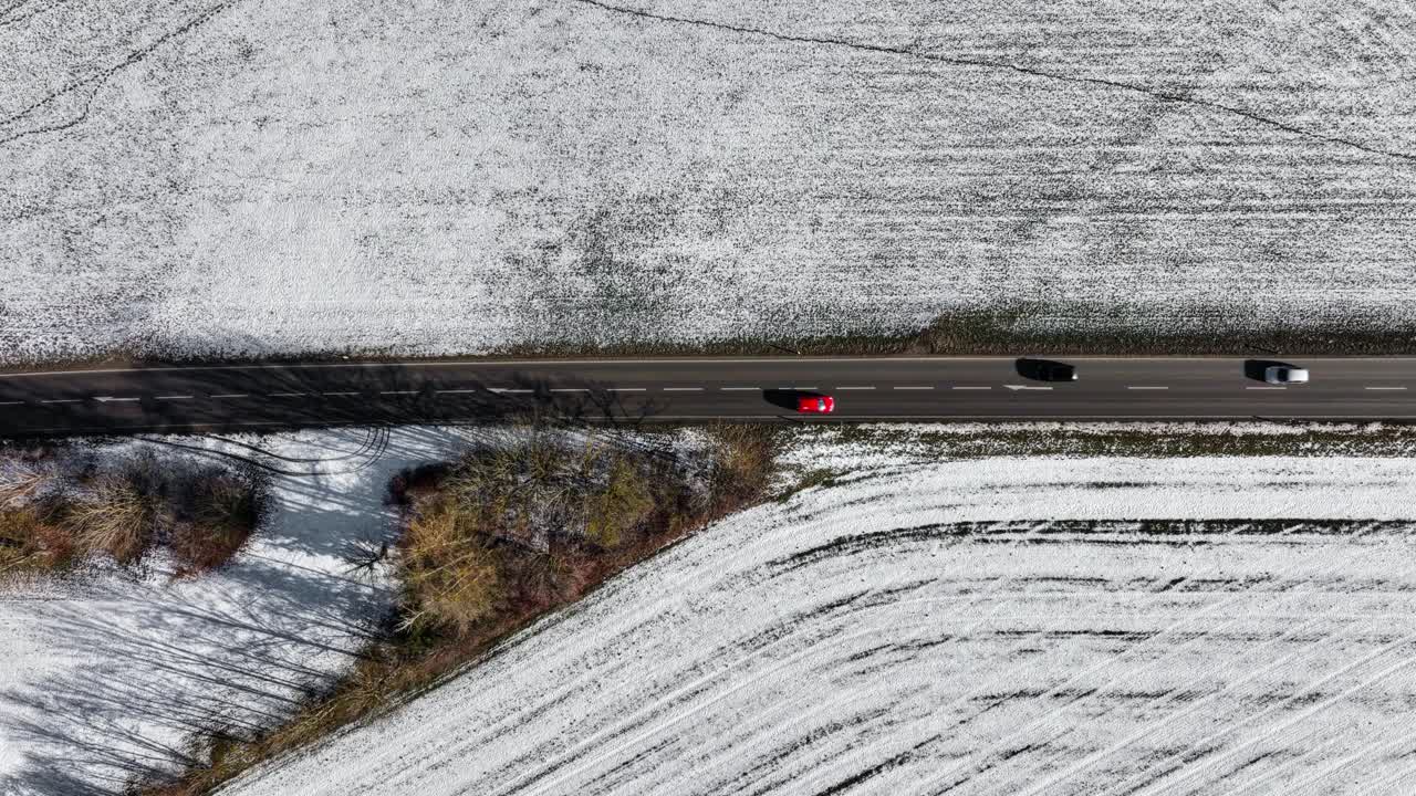 빨간 차가 겨울 도로를 따라 위에서 아래로 공중 촬영으로 똑바로 운전하고 있습니다.