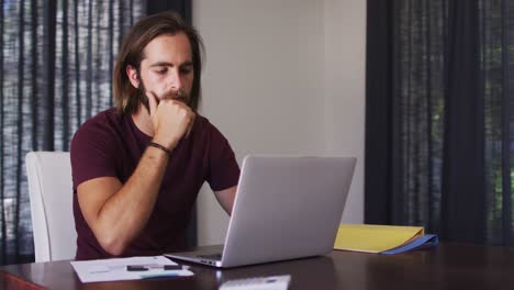 hombre caucásico usando una computadora portátil mientras trabaja desde casa