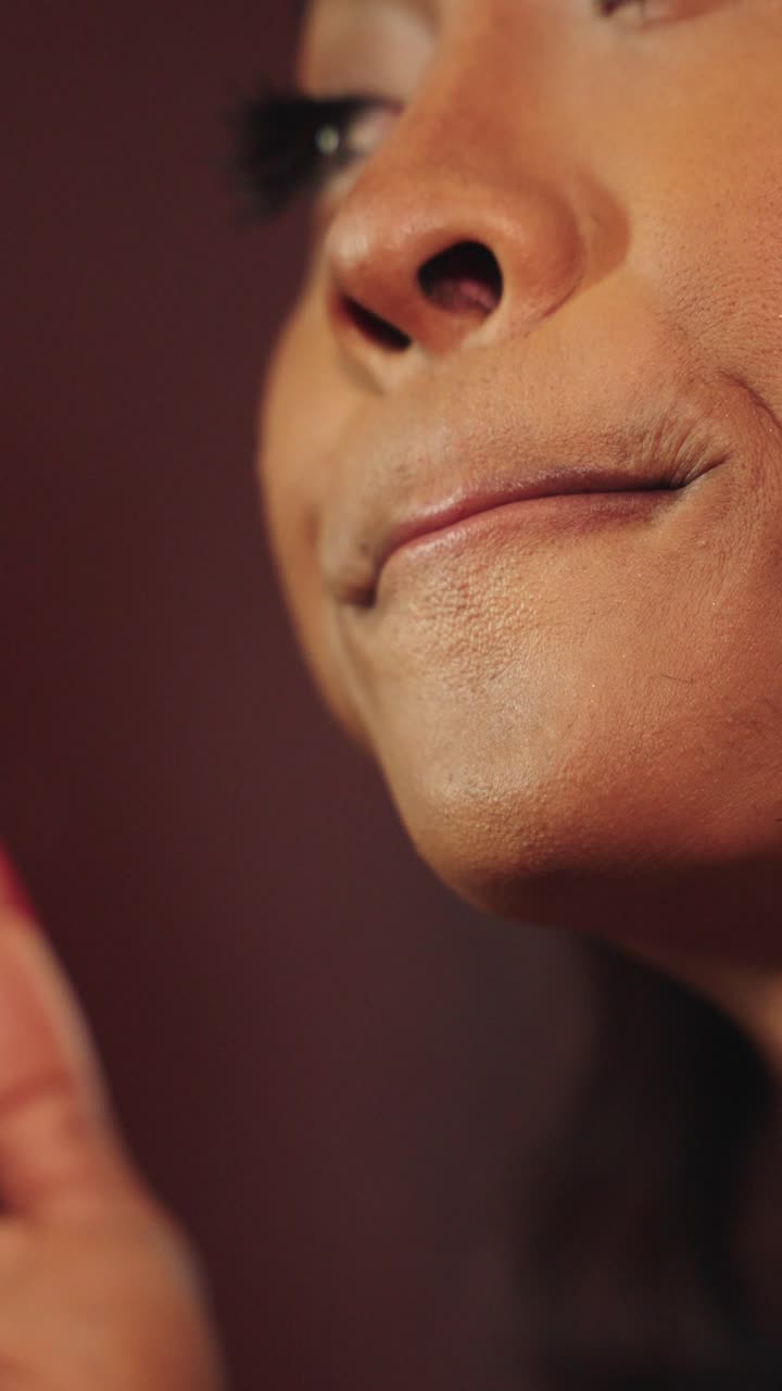 Close-up of a woman's face and hands with red nails