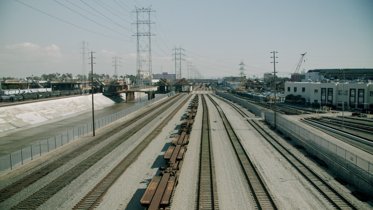 Train Tracks and Industrial Landscape with Power Lines and Concrete River