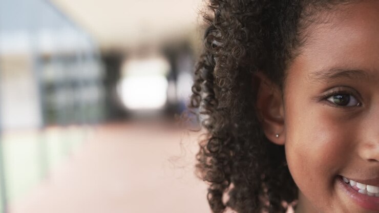 Close-up seorang gadis blasteran tersenyum dengan rambut keriting, dengan ruang salin, di sekolah