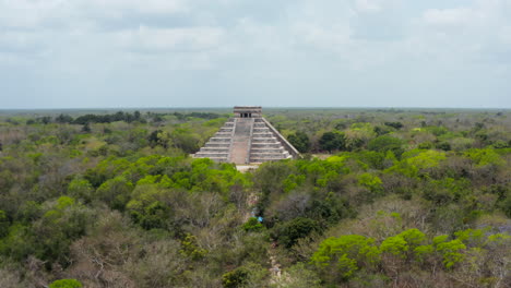 Rising-up-footage-of-remains-of-old-Maya-town-surrounded-by-vast-rain-forest.-Historical-monuments-of-pre-Columbian-era,-Chichen-Itza,-Mexico.