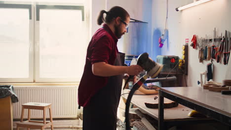 Man-uses-orbital-sander-gear-after-consulting-schematics,-assisted-by-apprentice