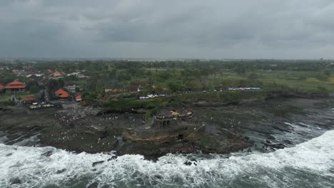 Los-Turistas-Caminan-Sobre-Las-Rocas-De-La-Costa-Mientras-Las-Olas-Rompen-En-El-Templo-De-Tanah-Lot.