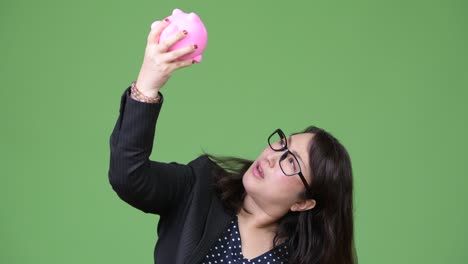 mature beautiful asian businesswoman holding piggy bank
