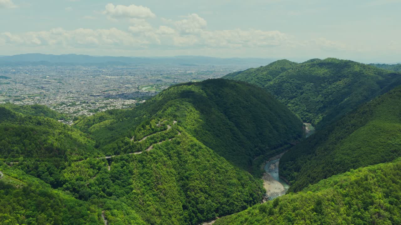 Establishing Aerial wide landscape of Kyoto City in Japan, Arashiyama river along green lush mountains