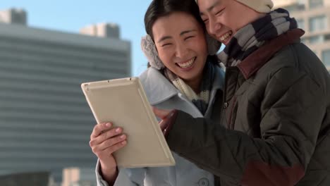 couple in warm clothes using tablet