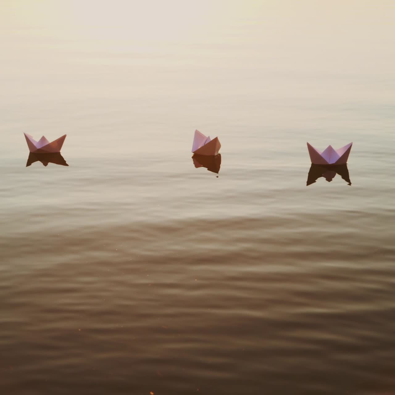 White paper boats float in the lake water at sunset. Origami