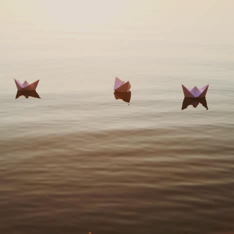 white paper boats float in the lake water at sunset. origami
