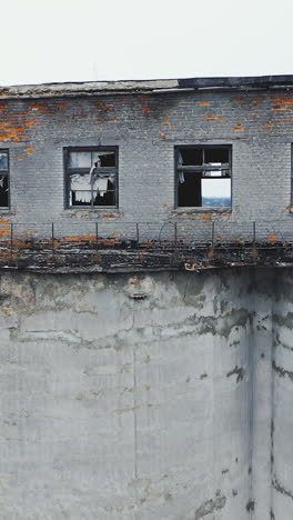 broken windows and walls of an old chemical plant. moss-covered concrete vault. ruins of industrial buildings. aerial view. vertical video