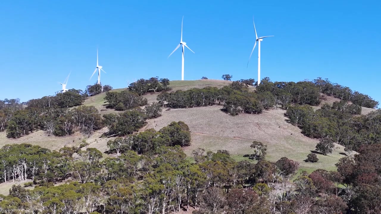 Vista aerea di turbine eoliche rotanti su una collina rurale a Matheson, Nuovo Galles del Sud
